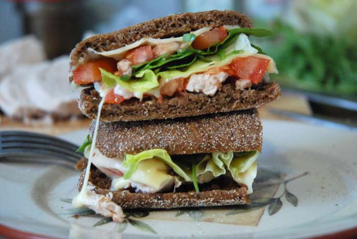 Сэндвич из черного хлеба с лососем, салатом-латуком и помидорами